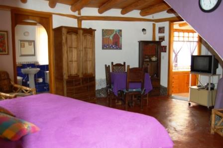 Dormitorio con cama junto a una pared morada.