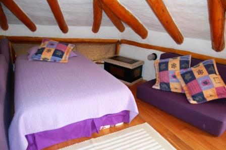 Dormitorio bajo techo de madera con vigas expuestas.