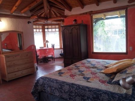 Dormitorio con cama y armario junto a la ventana.